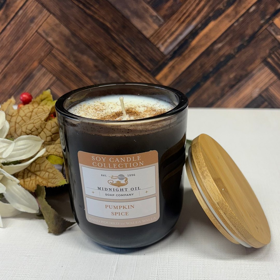 Soy candle labeled 'Pumpkin Spice' from Midnight Oil Soap Company on a wooden surface with decorative elements.